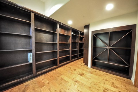 A long hallway with wood floors and dark wood bookshelves.