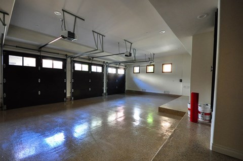 A large empty room with a concrete floor and basketball hoops on the ceiling.