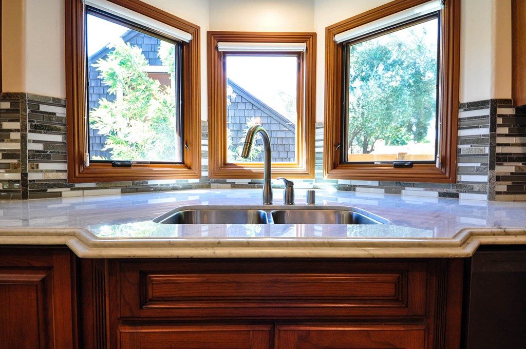 A kitchen with a sink and three windows.