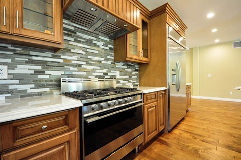 A kitchen with wooden cabinets and a stone backsplash.