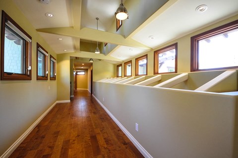 A long hallway with wood floors and windows on the side.