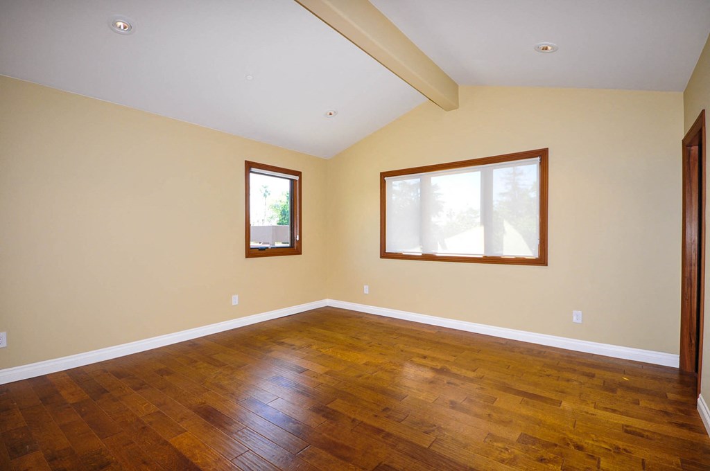 A room with wooden floors and two windows.