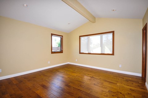 A room with wooden floors and two windows.