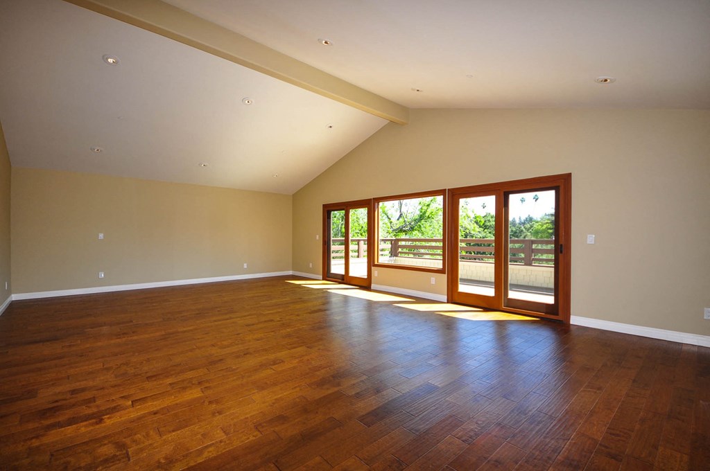 A room with wooden floors and a large window with a view of trees.