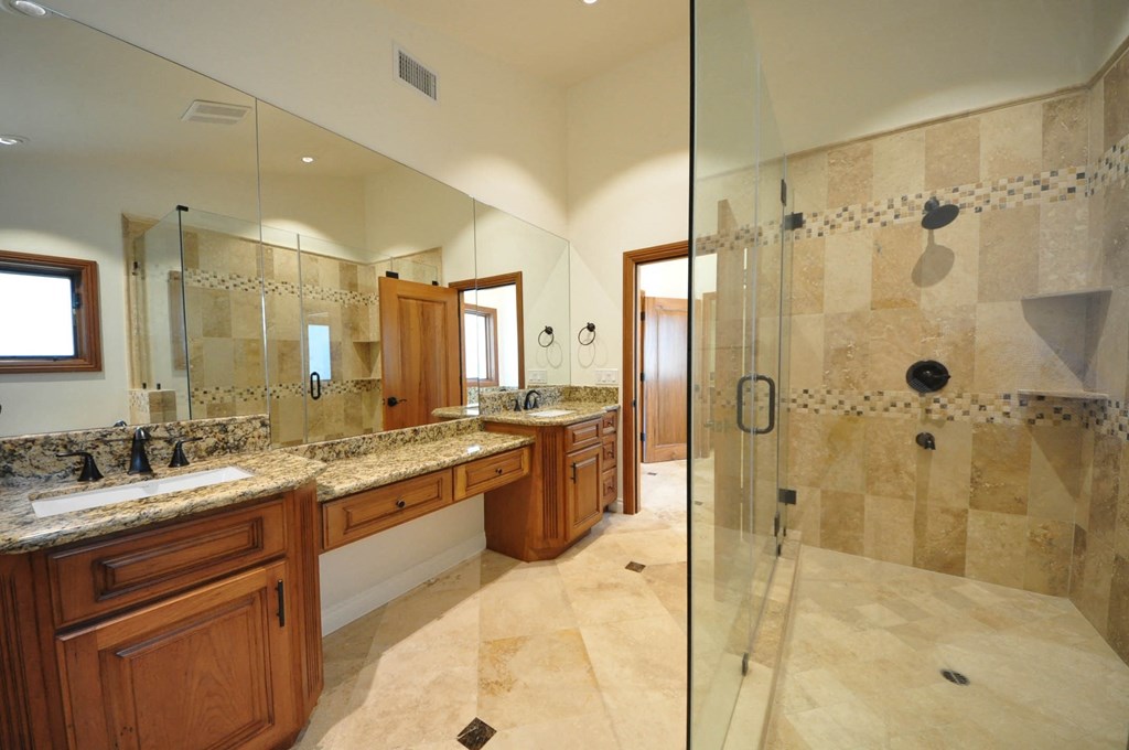 A bathroom with a walk-in shower and double sinks.