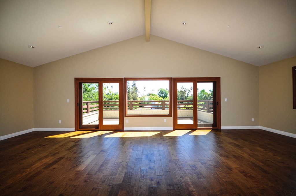 A room with wooden floors and a large window with a view of trees.