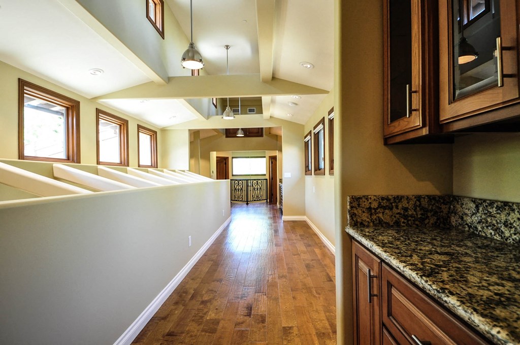 A long hallway with wood floors and marble countertops.