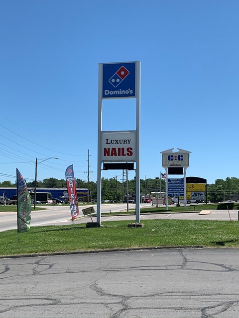 A Domino's pizza sign is in front of a nail salon.