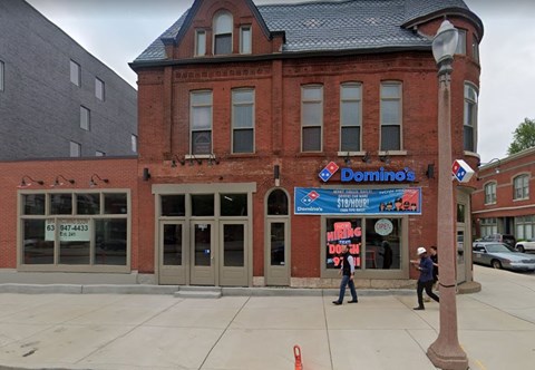 A Domino's Pizza restaurant with a blue and red signboard and a phone number on the window.