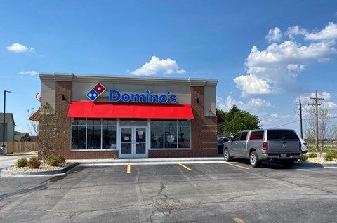 A Domino's Pizza store with a car parked in front.
