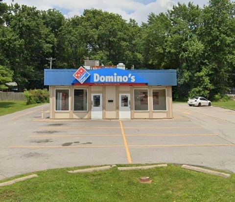 A Domino's Pizza restaurant with a blue awning and a white car parked in front.