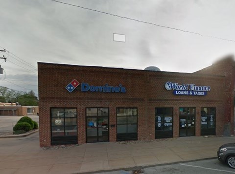 A brick building with a Domino's Pizza and World Finance loans and taxes sign on it.
