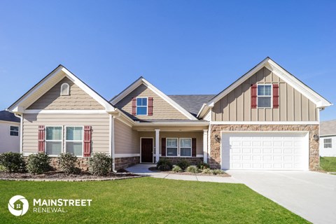 a beige and brick house with a garage door and lawn