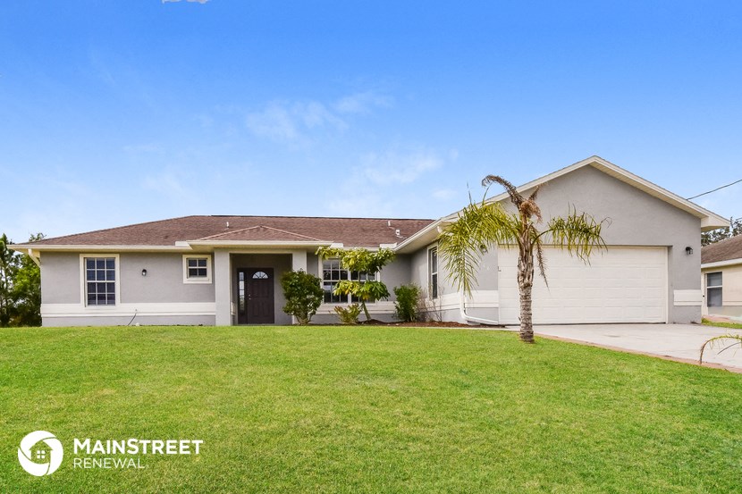 a white house with a lawn and a palm tree