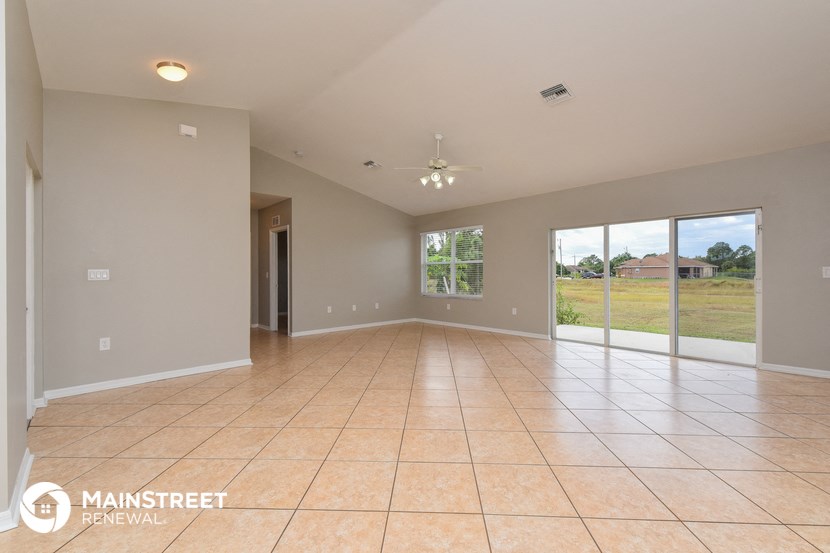 a spacious living room with tile flooring and sliding glass doors