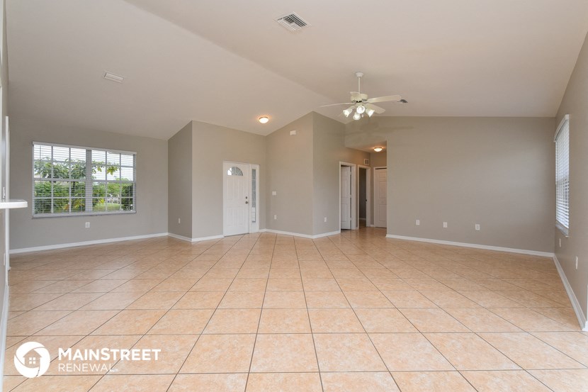 the spacious living room with tile flooring and a ceiling fan
