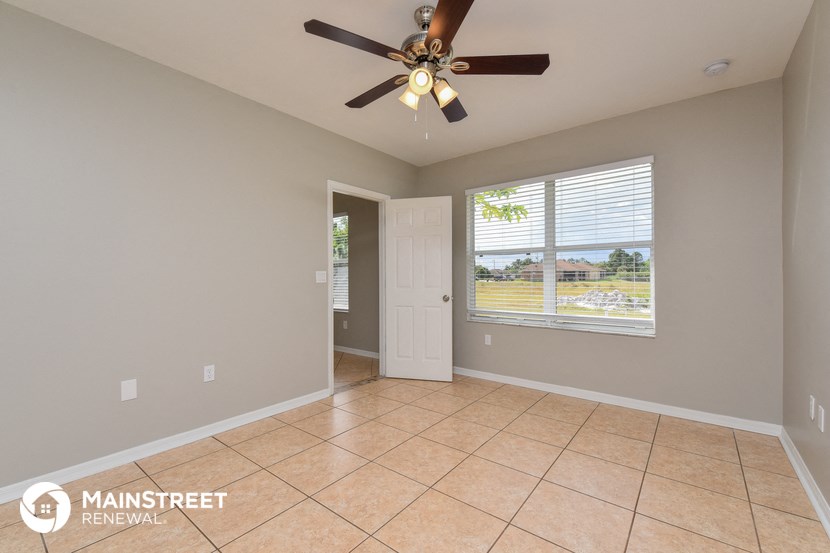 an empty living room with a ceiling fan and a window