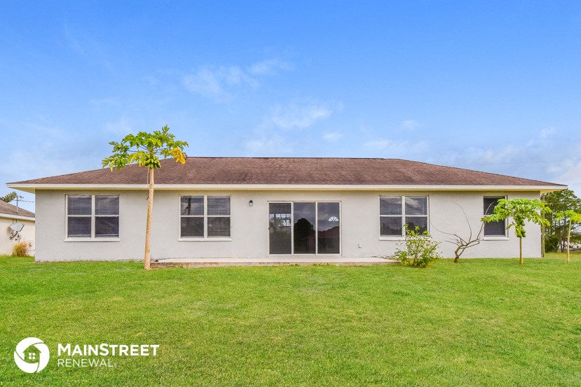 a small white house with a green lawn and a blue sky