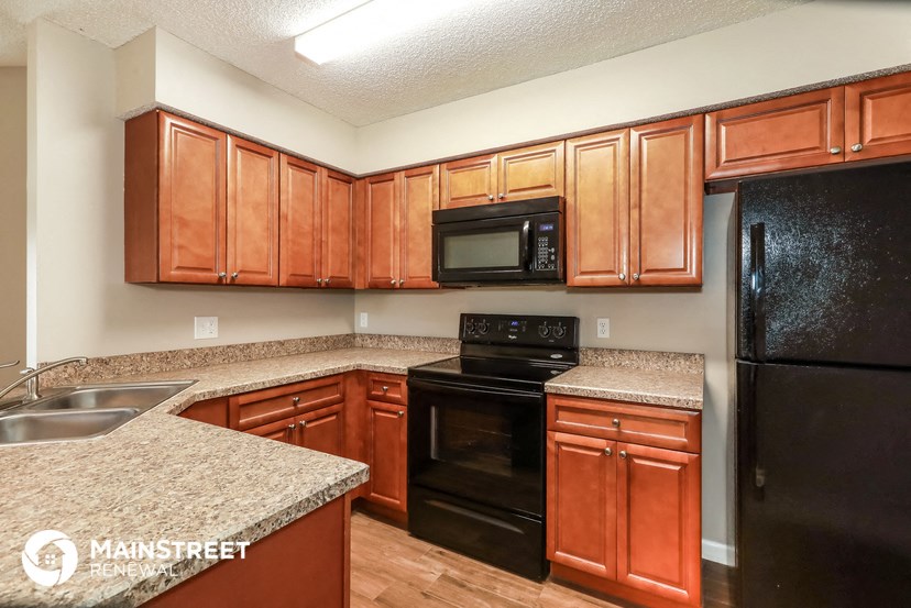 a kitchen with wood cabinets and black appliances and granite counter tops