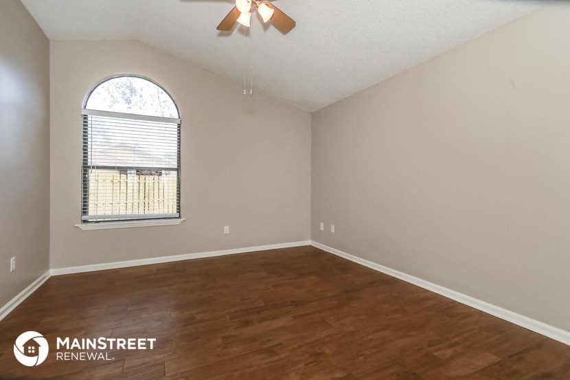 the spacious living room with hardwood flooring and an arched window