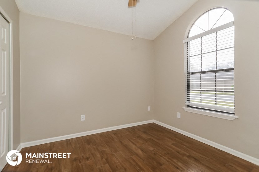 the spacious living room with wood flooring and an arched window
