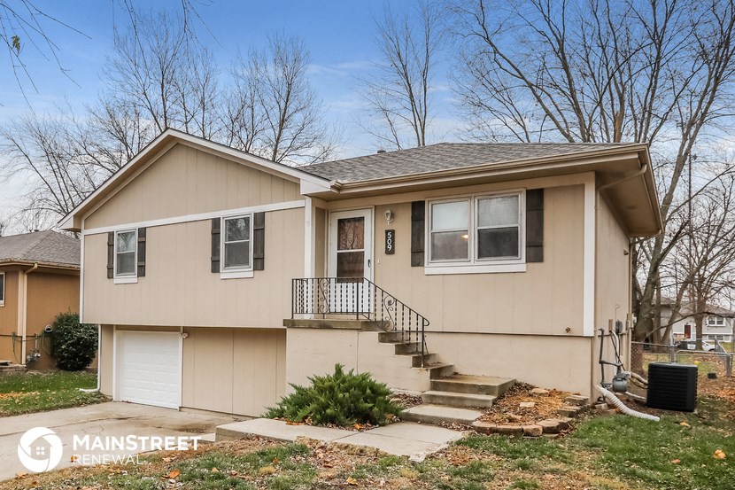 a beige house with stairs and a front yard