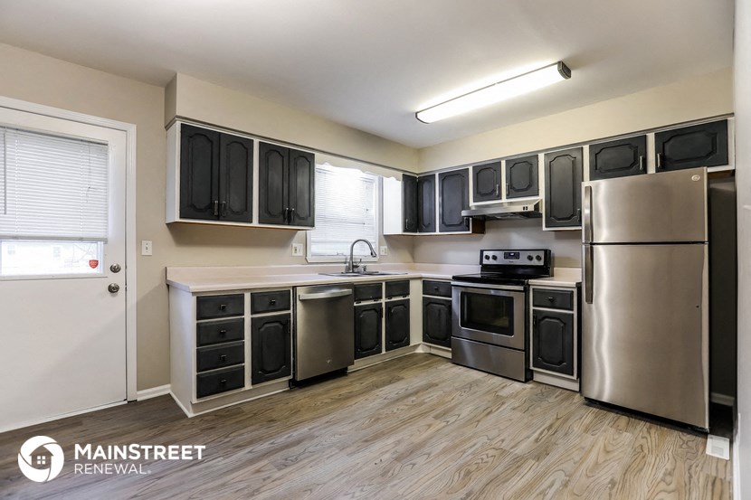 the kitchen of an apartment with stainless steel appliances and black cabinets
