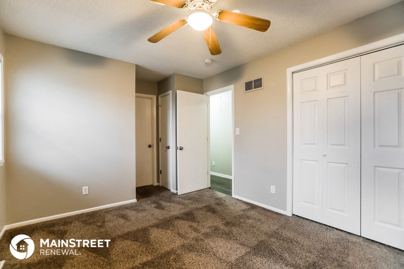 the spacious living room with carpeted floors and a ceiling fan