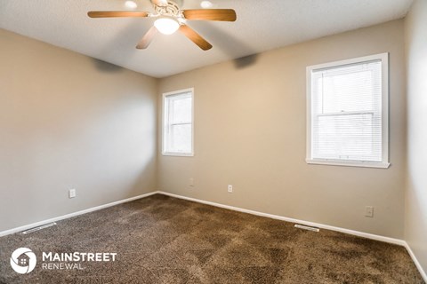 the spacious living room with carpet and a ceiling fan
