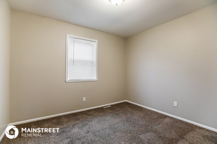 the spacious living room of a home with carpet and a window