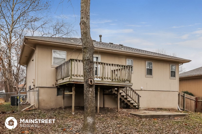 the back of a house with a deck and a tree