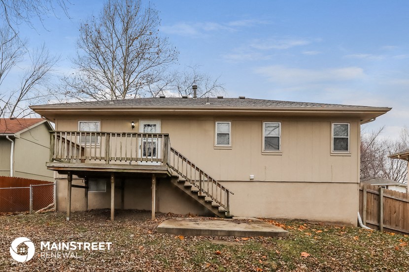 the front of a tan house with a deck and a backdoor