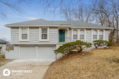 a white house with a green door and a driveway