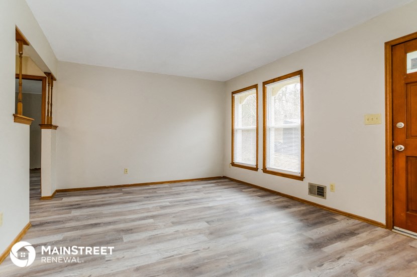 the living room of a home with wood floors and white walls