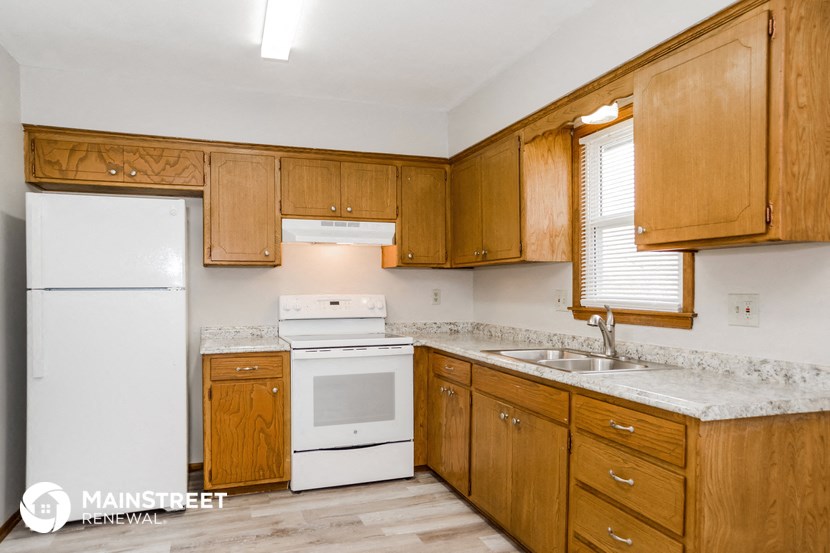 a kitchen with wooden cabinets and white appliances and a sink