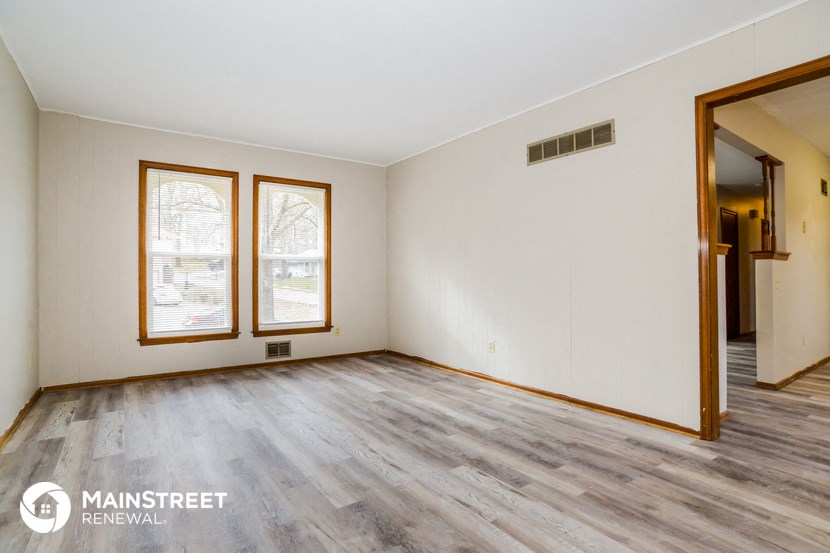 an empty living room with white walls and wood floors