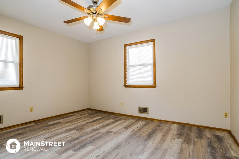 the living room of an empty house with wood floors and a ceiling fan