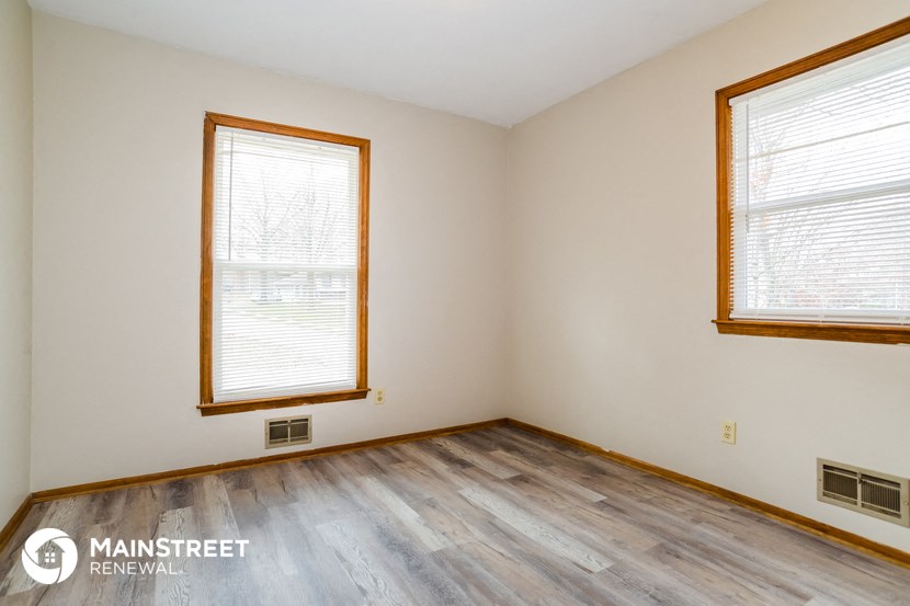 the living room of a home with wood flooring and two windows