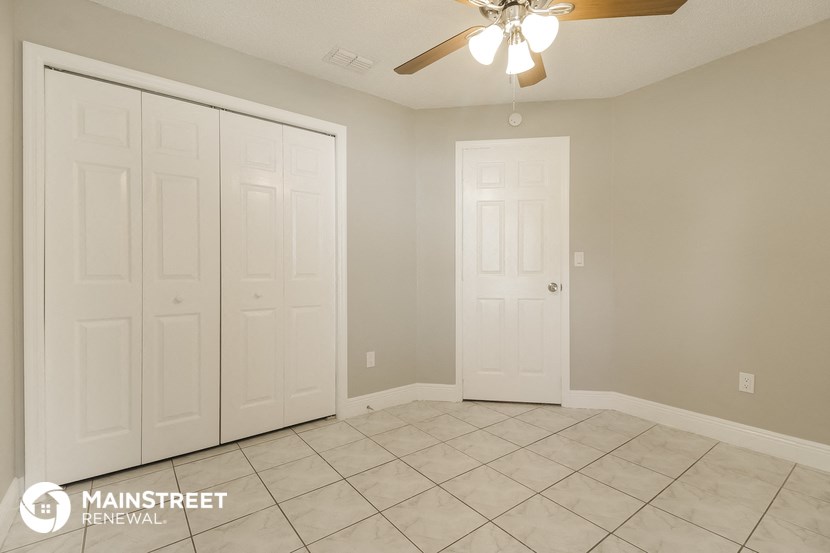 the living room of a home with a tile floor and a ceiling fan