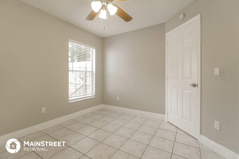 an empty living room with a white tile floor and a ceiling fan