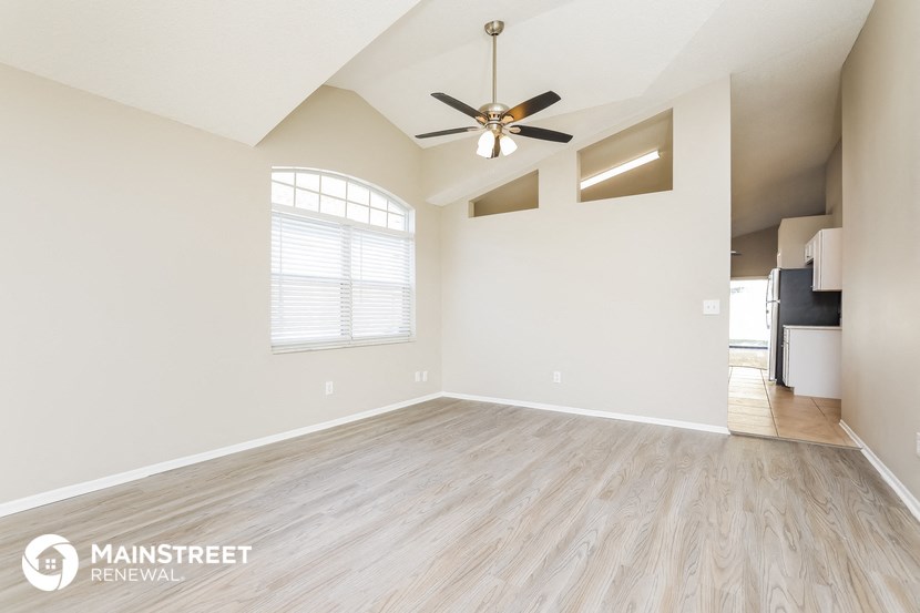 the spacious living room with hardwood floors and a ceiling fan