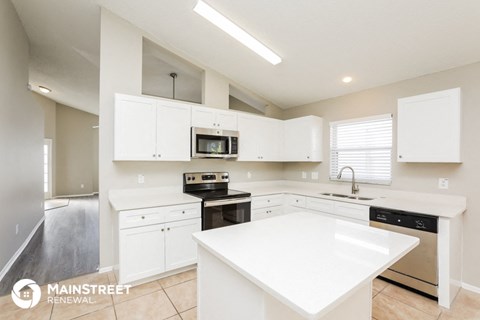 a large white kitchen with white counter tops and stainless steel appliances