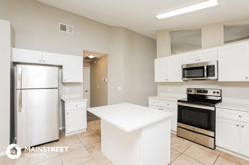 an all white kitchen with stainless steel appliances and a white counter top