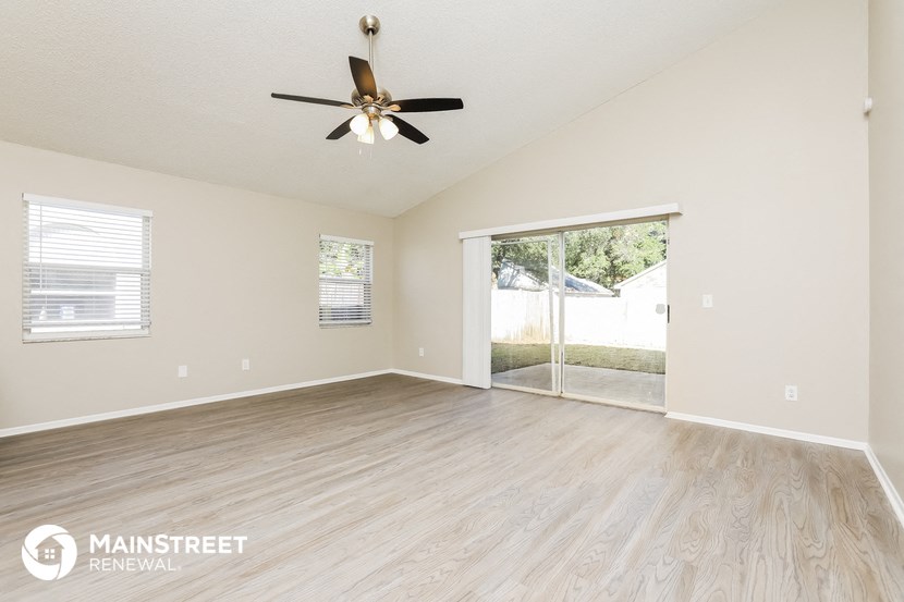 the spacious living room with wood flooring and a ceiling fan