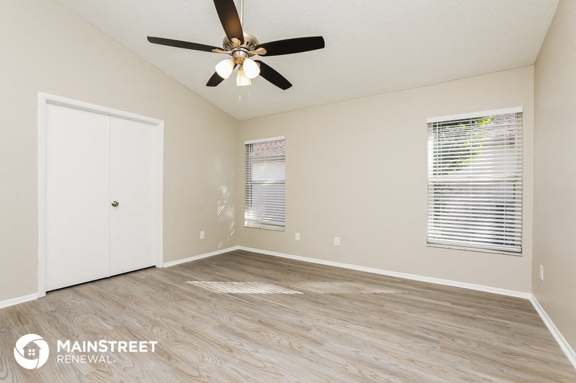 the spacious living room with wood flooring and a ceiling fan