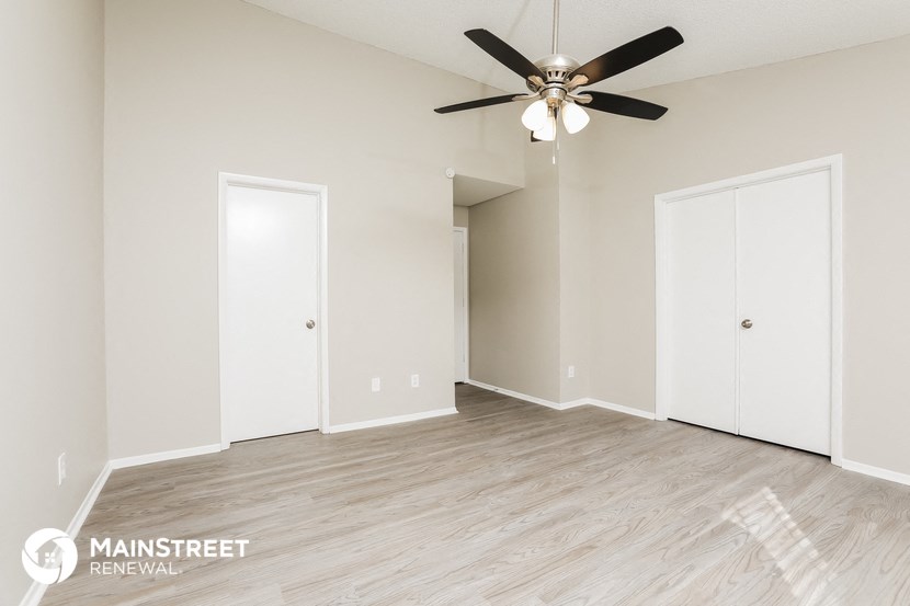 the living room of an apartment with wood flooring and a ceiling fan
