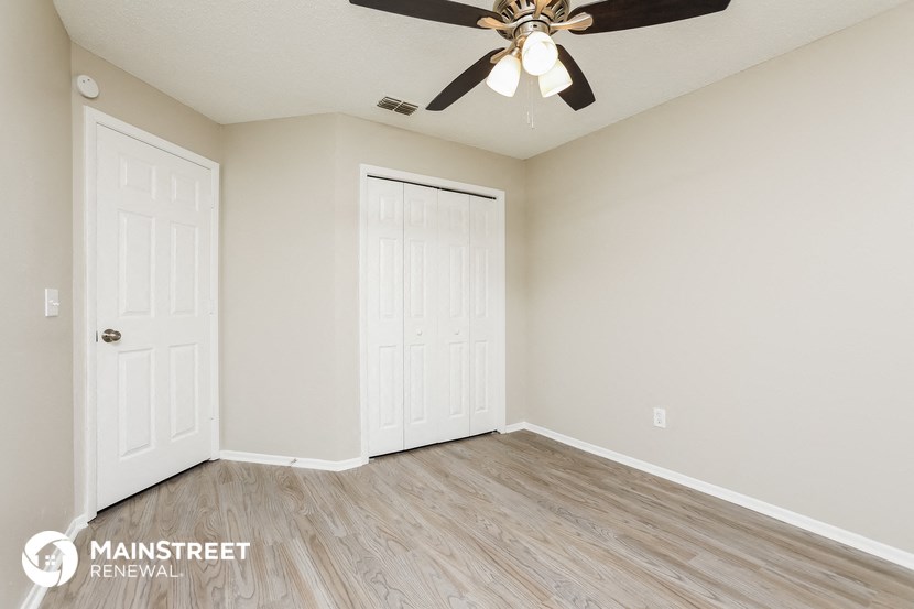 the spacious living room with two closet doors and a ceiling fan