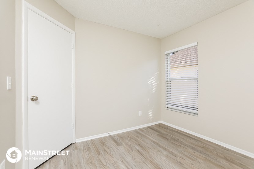 the living room of an apartment with wood flooring and a window