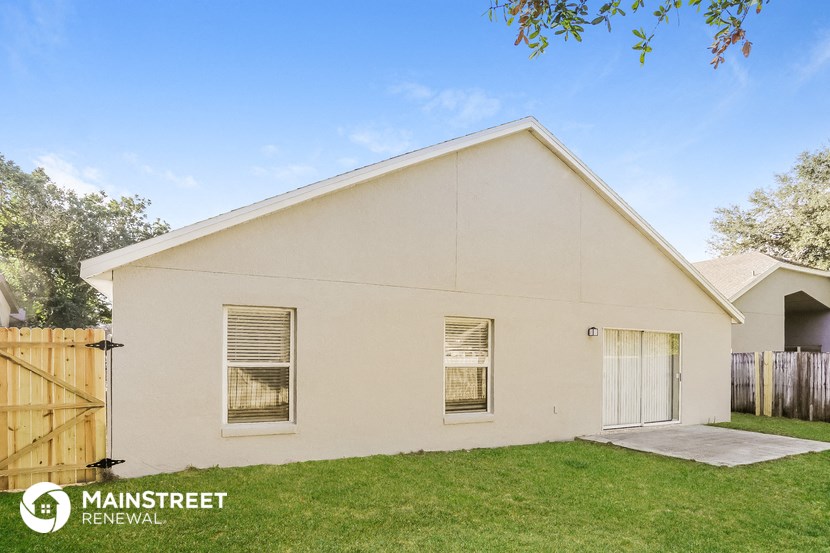 the outside of a white house with a yard and a wooden fence