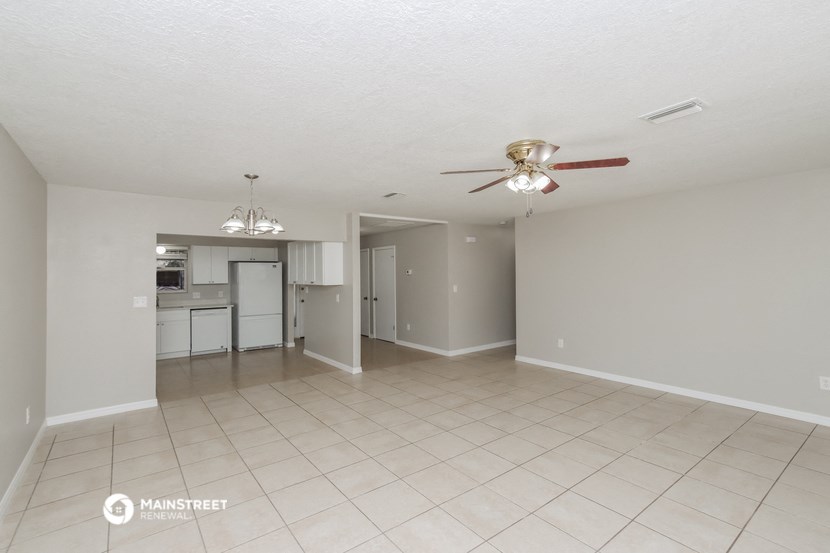 an empty living room and kitchen with a ceiling fan